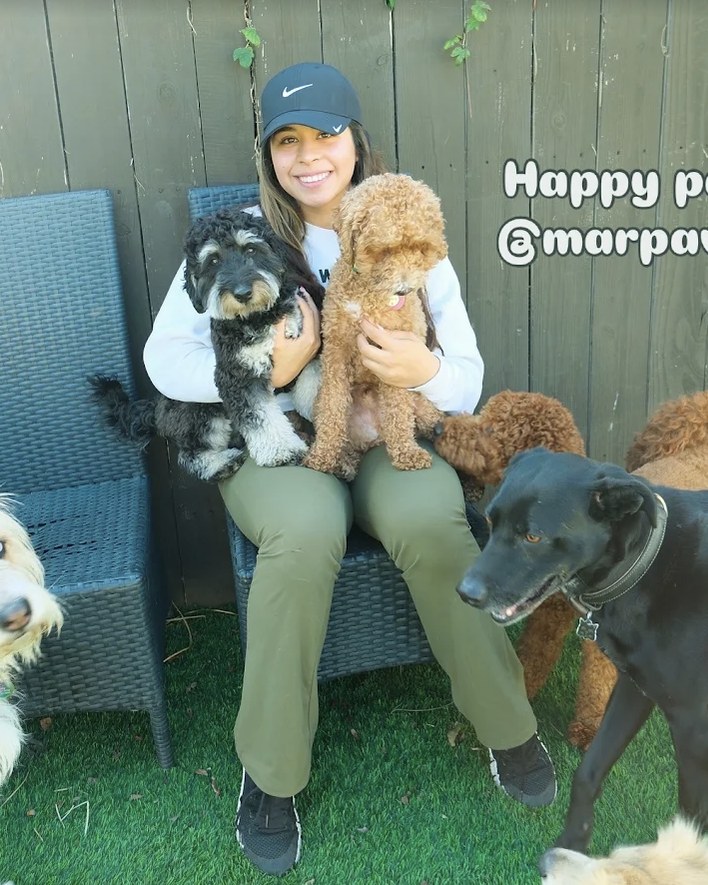 Mariam sitting in the yard surrounded by the dogs in her care
